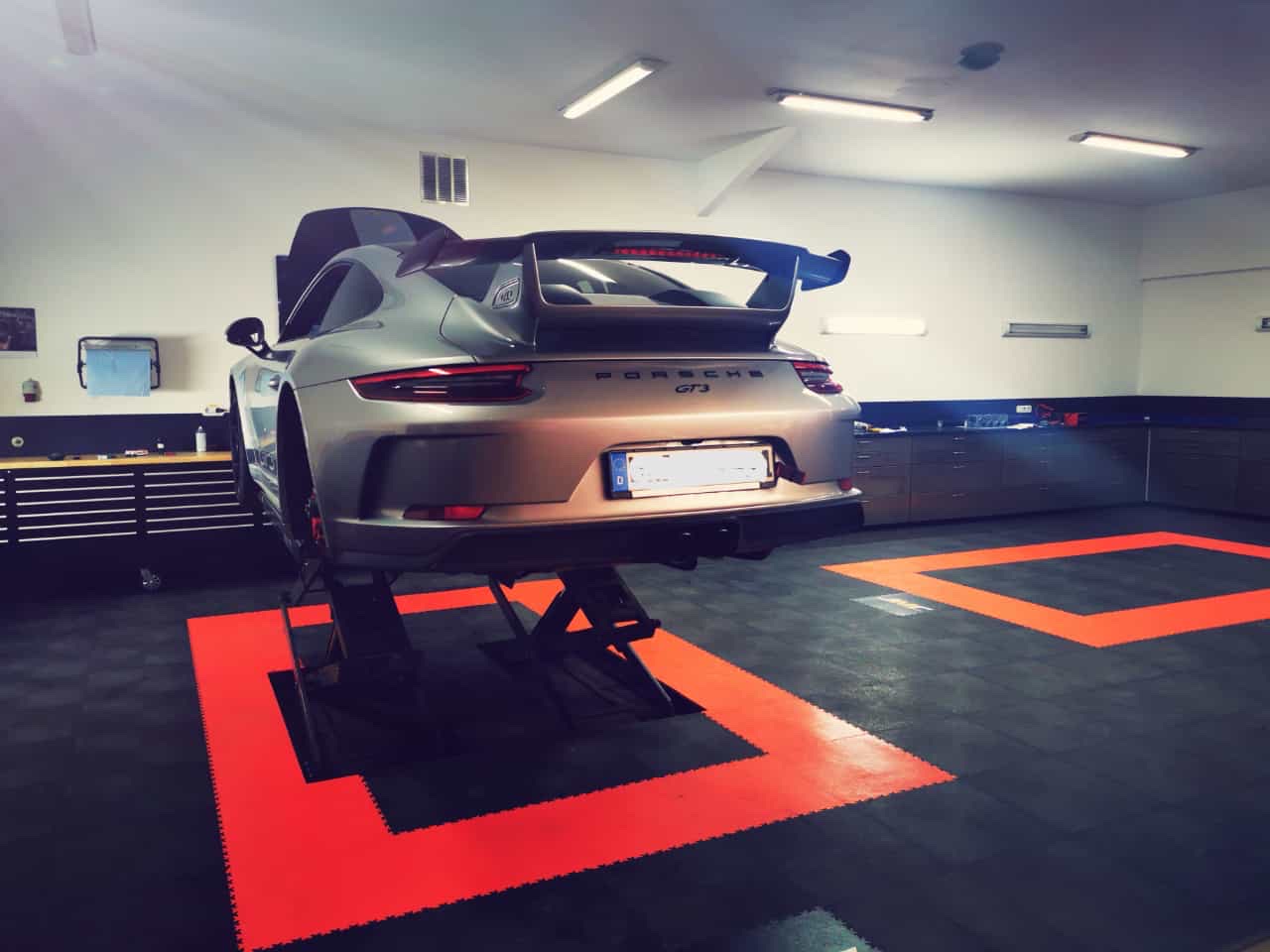 Coche sobre un elevador en un taller alemán impecable, en plena revisión